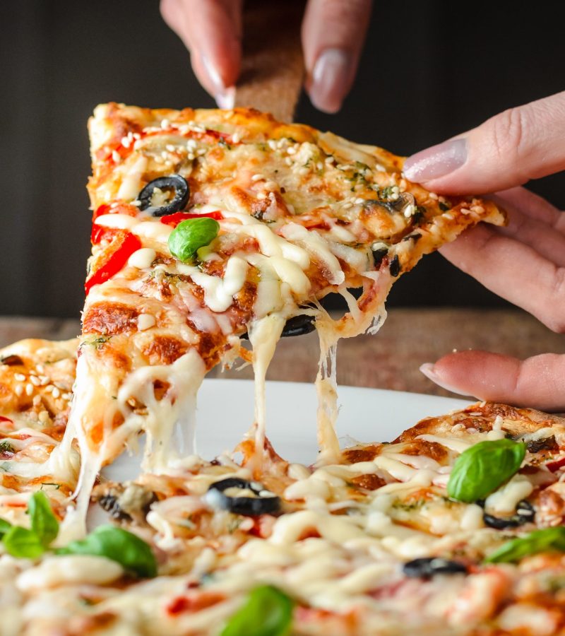 woman takes a piece of pizza woman's hands takes a piece of pizza with a pulling cheese, close-up